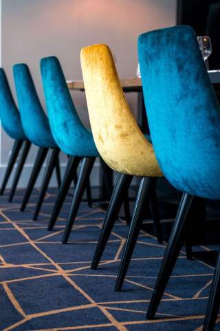 4 chaises bleues et 1 chaise beige alignées dans le restaurant de l'Hôtel de la Paix, restaurant au centre ville de Reims