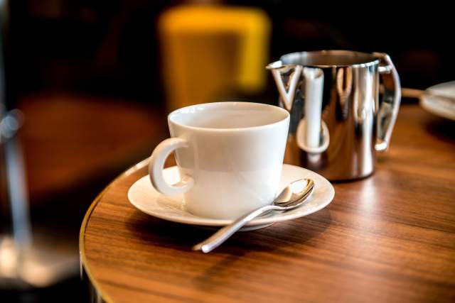 Tasse de café sur une table en bois au Bar La Paix à Reims, bar de l'Hôtel de La Paix