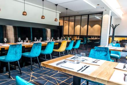 Salle de restauration avec des chaises bleues alignées contre le comptoir du restaurant Café de la Paix, située rue Buirette au centre-ville de Reims